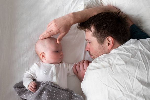 Sleeping father and cute child resting together in bed. - Photo, Image