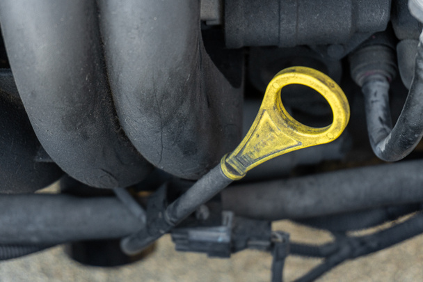 Close-up with selective focus of a car's oil dipstick inserted into the engine. - Photo, Image