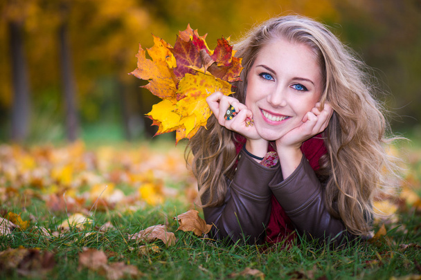 vrouw liggend op herfst bladeren, buiten portret - Foto, afbeelding
