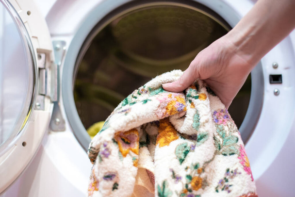 loading dirty laundry into a washing machine - 写真・画像