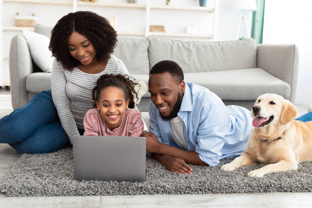 Famiglia nera utilizzando pc relax con cane a casa - Foto, immagini