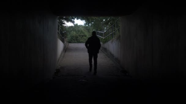 Silhouette eines erwachsenen Mannes beim Betreten einer dunklen Tunnelunterführung. Abgeriegelt - Filmmaterial, Video