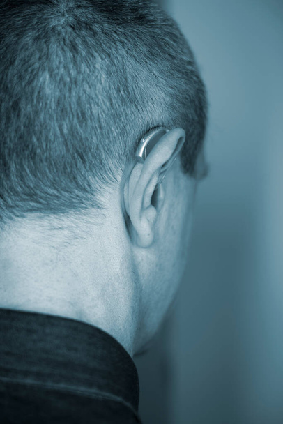 Modern dijital işitme cihazı orta yaşlı 50 'li yaşlarda bir adamın kulağında - Fotoğraf, Görsel