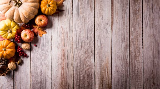 Thanksgiving and autumn composition. Pumpkin, apple,red berry and autumn leaves on dark wooden background. Flat lay, top view with copy space. - Photo, Image