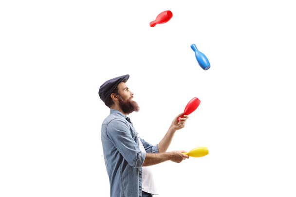 Profile shot of a juggler juggling with clubs isolated on white background - 写真・画像