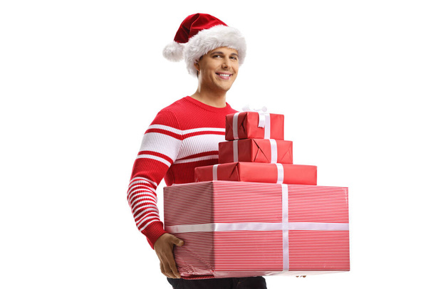 Man with a christmas santa hat holding a pile of presents isolated on white background - 写真・画像