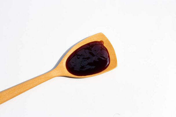 Устричный соус в деревянной лопатке на белом фоне. - Фото, изображение