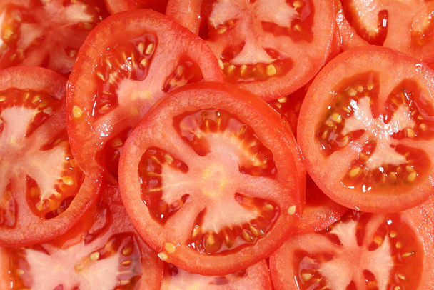 Voedsel achtergrond cirkels snijdt rode rauwe tomaat close-up - Foto, afbeelding