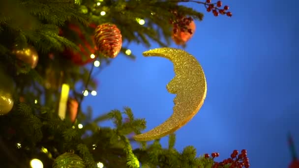Χριστουγεννιάτικα στολίδια στο δέντρο του δρόμου, ημισέληνος αναπτύσσεται στον άνεμο κατά το μπλε του ουρανού το βράδυ, η έννοια της διακόσμησης για τα Χριστούγεννα - Πλάνα, βίντεο