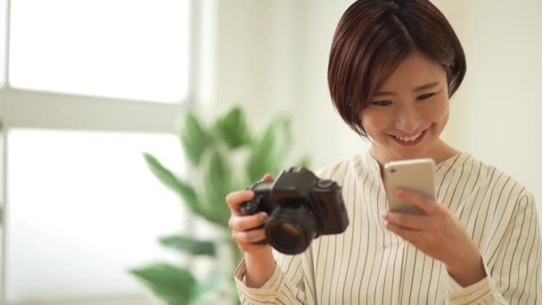 Une femme visualisant des images prises avec un appareil photo reflex mono-objectif et un smartphone - Séquence, vidéo