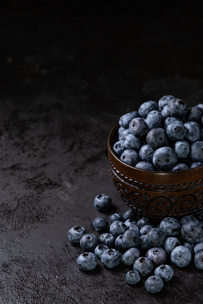 Świeże soczyste jagody w misce na czarnym tle. Fotografia małoobrazkowa - Zdjęcie, obraz