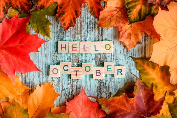 Flatlay, fogliame d'acero autunnale, iscrizione "ciao ottobre" in lettere di legno sul tavolo. Sfondo autunno - Foto, immagini
