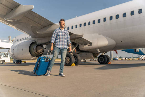 Voyageur homme caucasien descendre de l'avion avec valise dans l'aéroport - Photo, image