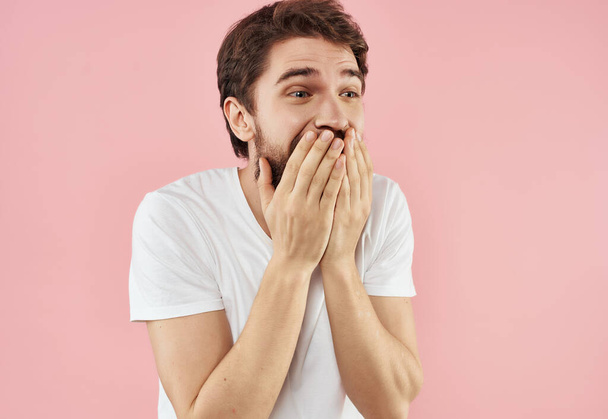 hombre emocional en una camiseta blanca mano gestos fondo rosa - Foto, imagen