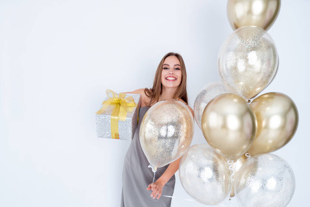 Photo of smiling lady holds large wrapped giftbox and many air balloons. came to party. Celebration  - Foto, Bild