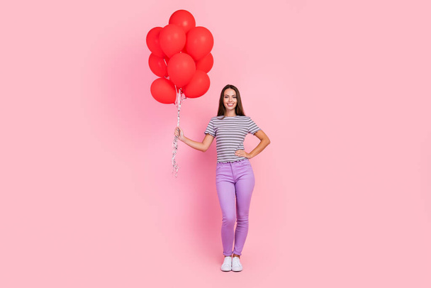 Photo of pretty charming young lady wear striped outfit smiling holding balloons bouquet isolated pink color background - 写真・画像