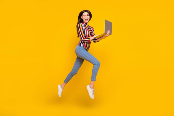 Повна довжина тіла фото дівчини в повсякденному одязі стрибає перегляд Інтернету на ноутбуці ізольований яскраво-жовтий кольоровий фон
 - Фото, зображення