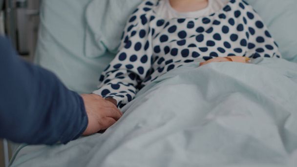 Closeup of father taking sick daughter hands after suffering medical surgery - Valokuva, kuva
