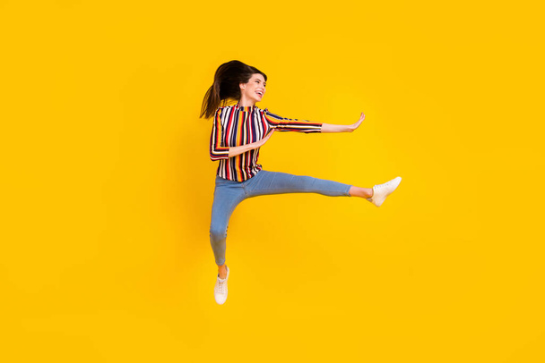 Full length body size photo girl in casual clothes jumping practising martial arts isolated bright yellow color background - Foto, afbeelding