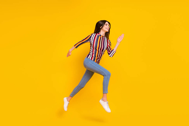 Full size profile side photo of young woman happy positive smile jump go walk run hurry isolated over yellow color background - Foto, Bild