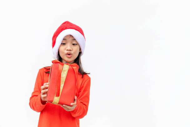 Happy Asian child in Santa red hat holding Christmas presents. Christmas time.on white background. - Photo, Image