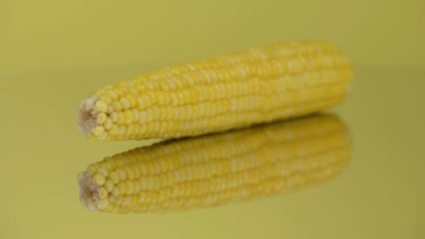 Una mazorca de maíz hervido en un espejo amarillo. Primer plano extremo. Vista lateral. El foco se mueve a lo largo de la mazorca de maíz. Imágenes de vídeo 4K UHD 3840X2160. - Metraje, vídeo
