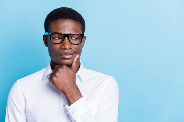 Photo of pretty serious dark skin man wear white shirt arm chin looking empty space isolated blue color background - Fotó, kép
