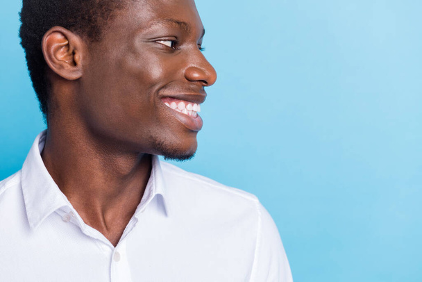 Photo of charming sweet dark skin guy dressed formal shirt smiling looking empty space isolated blue color background - Фото, зображення