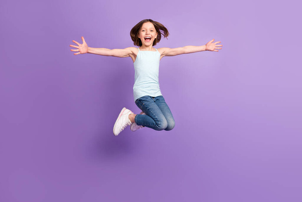 Full body photo of attractive crazy happy small girl jump up air enjoy free time isolated on purple color background - Foto, Imagem