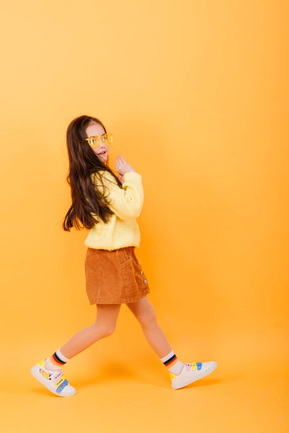Close-up portrait of cute little girl. Studio shot over yellow background. Childhood concept. - 写真・画像