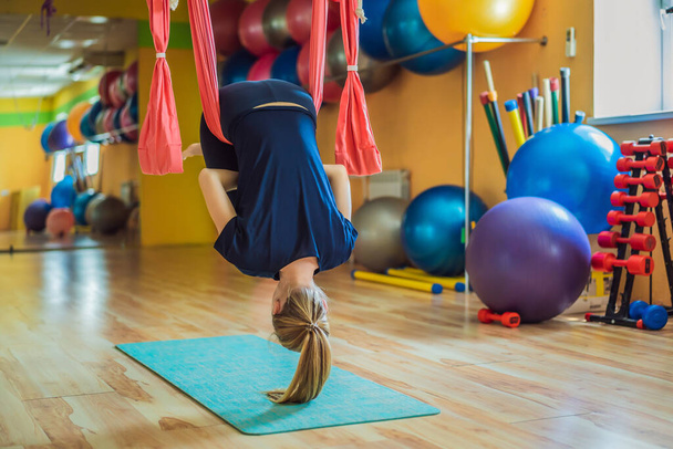 Young beautiful woman practicing aerial yoga in gym. Lifestyle - Фото, зображення