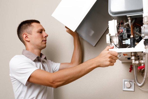 Plumber attaches Trying To Fix the Problem with the Residential Heating Equipment. Repair of a gas boiler - 写真・画像