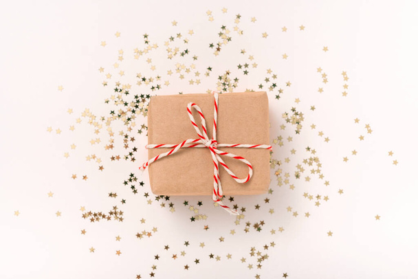 Ajándék doboz kézműves papír fehér-piros szilveszteri szalag és arany konfettisták egy bézs háttér fénymásolás, lapos laikus. Karácsony, esküvő - Fotó, kép