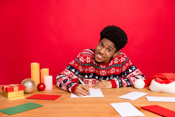 Photo of millennial nice brunet guy sit write wear holiday sweater isolated on red color background - Φωτογραφία, εικόνα