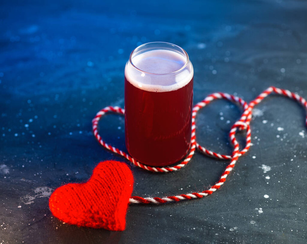 Bier is mijn Valentijn. Een glas ambachtelijk bier op tafel met een gebreid rood hart. - Foto, afbeelding