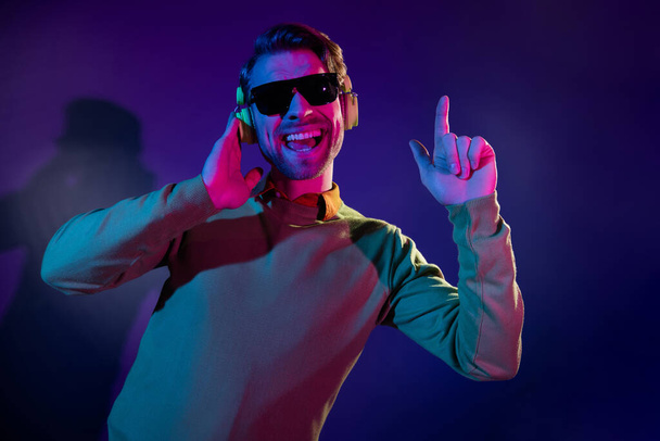 Photo portrait young man in sunglass smiling enjoying music in headphones isolated gradient violet color background - Fotoğraf, Görsel