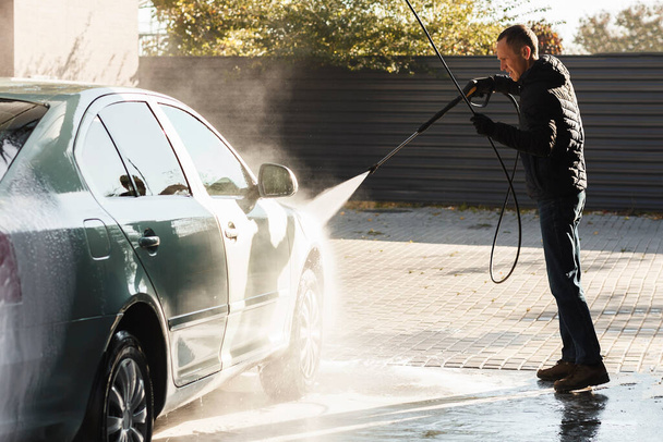 Washing car. Young man washes a car at a self-service car wash. - Foto, Imagem