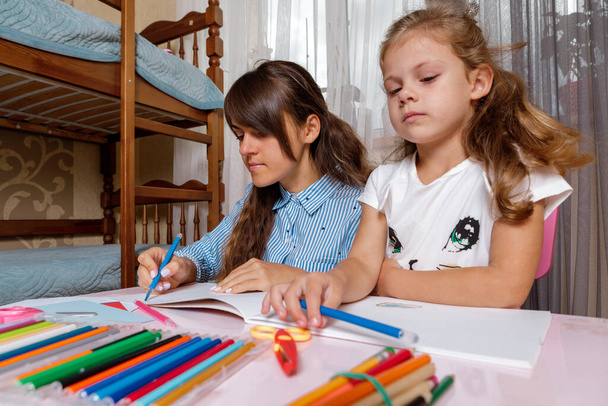 A mother with a child sits at the table and does homework. The child learns at home. Home schooling. - Photo, image