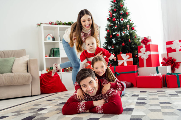 Photo of cute funny couple two children dressed new year pullovers smiling having fun together indoors house home room - Φωτογραφία, εικόνα
