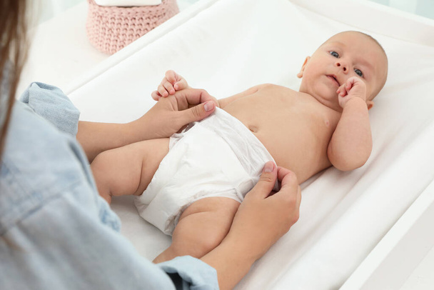 Mother changing her baby's diaper on table at home - Photo, image