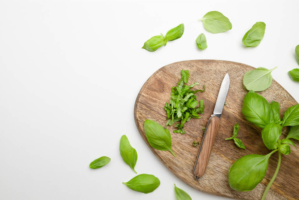 Fresh green basil herbs with a knife on wooden board background. Herbs and spices for cooking. Copy space - Zdjęcie, obraz