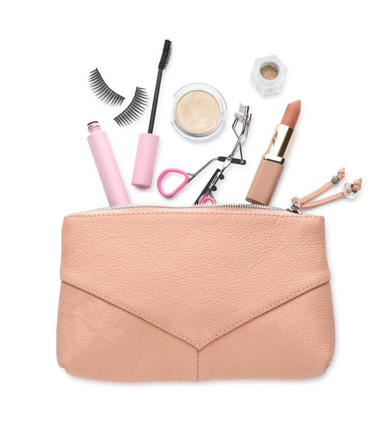 Cosmetic bag with eyelash curler and makeup products on white background, top view - Photo, image