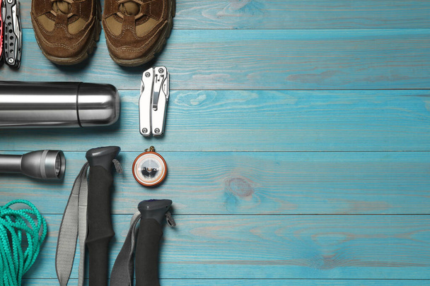 Flat lay composition with trekking poles and other hiking equipment on light blue wooden background, space for text - Fotoğraf, Görsel