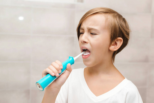Kid brushing teeth with electic brush in bathroom. Dental hygiene every day. Health care, childhood and dental hygiene. Happy boy cleaning teeth. Boy cares about health of his teeth. - Photo, Image