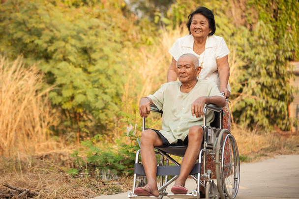 Seniorin schubst ihren behinderten Mann im Rollstuhl - Foto, Bild