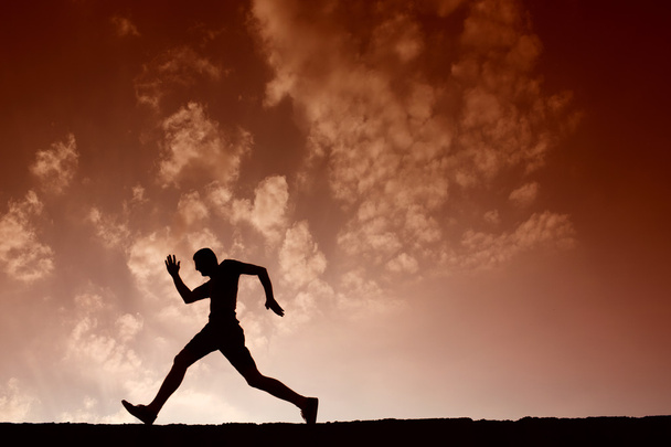 Silhueta de homem do esporte correndo com céu azul e nuvens nas costas
 - Foto, Imagem