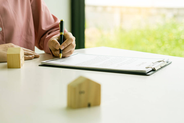Makler bieten Verträge für Hausversicherungen und Investitionskredite an. Ein Hausmodell und ein Kunde besprechen am Schreibtisch einen Hausvertrag, eine Versicherung oder einen Immobilienkredit. - Foto, Bild
