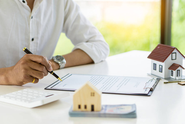 Real estate agents offer contracts for home insurance and investment loans. A house model and a customer discuss a home contract, insurance, or real estate loan at their office desk. - Fotó, kép