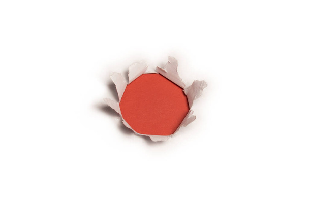 Un agujero en un papel blanco sobre un fondo rojo, espacio para copiar.  - Foto, imagen