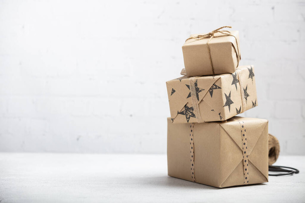 Stack of handcraft gift boxes on white brick background - 写真・画像